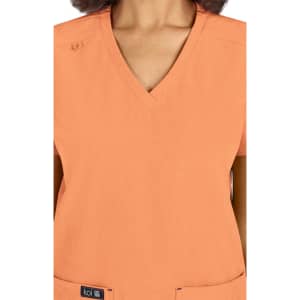 A scrub top in a soft orange colour with a V-neck design and a logo at the bottom.