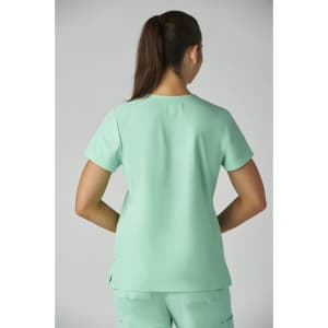 A woman is wearing a light mint green Becca Top, viewed from the back, with short sleeves and a relaxed fit.