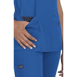 A blue medical top featuring two pockets, one with a polka dot fabric visible, and a logo on the side.