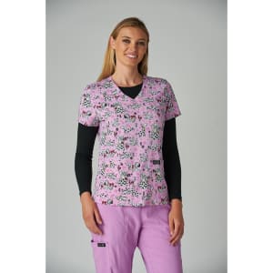 A woman wearing a pink floral printed top with a V-neck and black long-sleeve shirt underneath, paired with pink trousers.