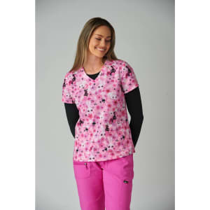 A pink scrubs top featuring a floral and bunny pattern, paired with a black long-sleeve underneath and pink pants.