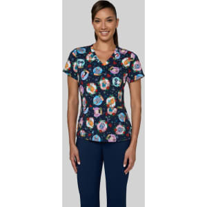 A patterned scrub top featuring vibrant illustrations on a navy background, paired with navy pants.