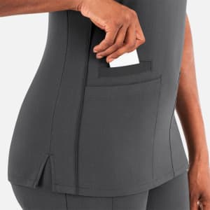 A grey layered V-neck top featuring a pocket for cards or small items. The design includes a small side vent.