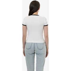 A white T-shirt with black trim on the sleeves, viewed from the back, paired with light blue jeans.