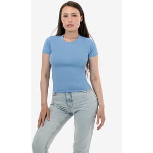 A model wearing a fitted light blue baby rib t-shirt paired with light jeans, with a minimalistic background.