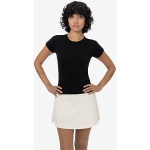A black cap sleeve baby tee paired with a light-coloured skirt, displayed on a model. The tee has a logo.