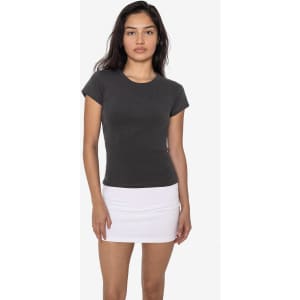 A cap sleeve garment dye baby tee in dark grey, styled with a white mini skirt. The model poses against a plain background.