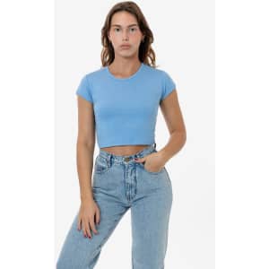 A light blue cap sleeve crop top paired with high-waisted jeans. The top has minimalistic styling and a logo.