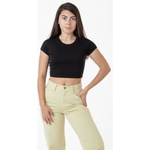 A black cap sleeve crop top paired with light beige trousers, featuring a model standing confidently.