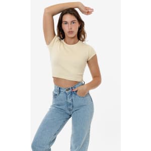 A model wears a light beige cap sleeve crop top with high-waisted jeans, posing against a plain background.