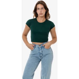 A model wears a fitted dark green cap sleeve crop top paired with high-waisted light blue jeans.