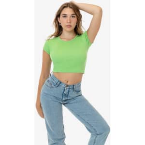 A model poses in a bright green cap sleeve baby rib crop top and light blue jeans. The top features a fitted design.