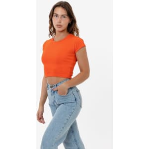 An orange cap sleeve crop top is displayed, paired with light blue jeans. The shirt features a simple design and has a logo.