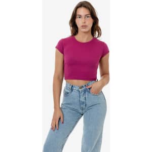 A cropped cap sleeve top in a vibrant magenta, paired with light blue high-waisted jeans. The shirt features a branding logo.