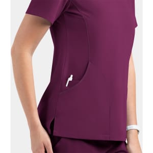 A women's contrast v-neck top in burgundy with a side pocket, featuring a subtle logo.