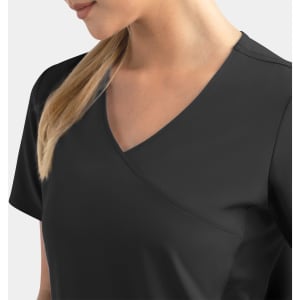 A mock wrap top in black with contrast panels, featuring a stylish V-neck design. The model has long hair.