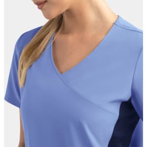 A women's mock wrap top in light blue with contrasting panels, featuring short sleeves and a v-neck design.