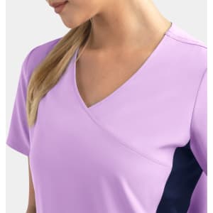 A lilac mock wrap top with contrast navy panels, featuring a v-neck design and short sleeves. It has a logo.