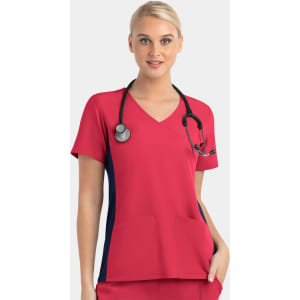 A bright pink women's mock wrap top with contrast navy panels, featuring two front pockets and a stethoscope.