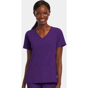 A women’s mock wrap top in purple with a V-neck and two front pockets. The model is smiling while wearing it.