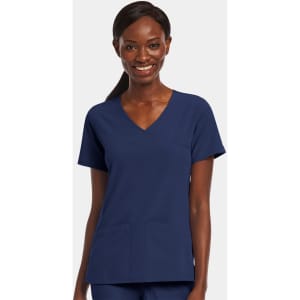 A woman wearing a navy blue mock wrap top with a V-neck and two front pockets. The top features a logo.