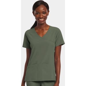 A woman smiles while wearing a green mock wrap top with two front pockets, featuring a logo.