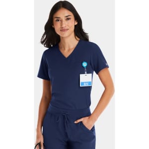 A navy v-neck top designed for women, featuring a tuckable design and a badge holder. The model has long dark hair.