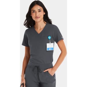 A woman in a grey V-neck top with a badge and logo, featuring a tuckable design.