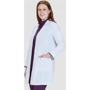 A white lab coat with a tailored fit, displayed on a model wearing a purple top underneath. The coat features pockets and a logo.