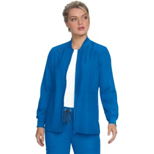 A woman wearing a fitted blue jacket, with a simple design and a standing collar, stands against a white background.