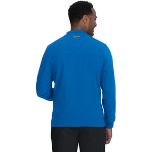 A blue jacket with a collar and long sleeves, featuring a back view of a man wearing it. The jacket has a logo.