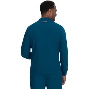 A man in a teal jacket is seen from the back, featuring a logo and a collar.