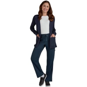 A woman wearing a navy Kori Sweater over a white top, paired with teal pants and sneakers.
