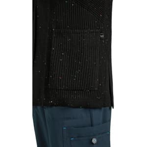 A black Kori Sweater featuring a textured design and a front pocket, paired with navy blue trousers.