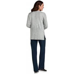 A grey Kori Sweater viewed from the back, paired with navy pants and featuring a logo.
