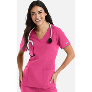 A woman wearing a pink double V-neck top with a stethoscope, featuring pockets and a logo on the sleeve.