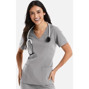 A woman wearing a grey double V-neck top with a stethoscope around her neck, smiling and posing.