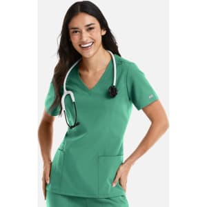 A woman smiles wearing a green double V-neck top, paired with a stethoscope around her neck. The top has pockets.