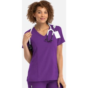 A woman wearing a purple mock wrap top with a stethoscope around her neck. The top features a logo.