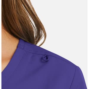 A close-up of a women's mock wrap top in purple, featuring a decorative loop on the shoulder.