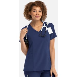 A navy mock wrap top with short sleeves, featuring a stethoscope and a tag, worn by a woman with curly hair.