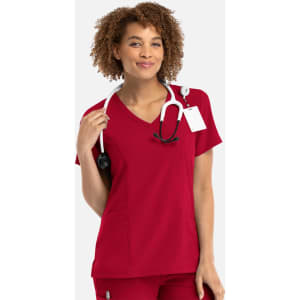 A mock wrap top in a vibrant red colour, featuring a v-neck design and a logo, worn by a smiling model with a stethoscope.