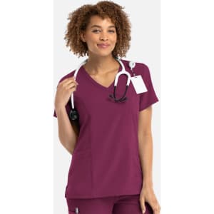 A woman in a plum-coloured mock wrap top, wearing a stethoscope around her neck, with a logo visible.