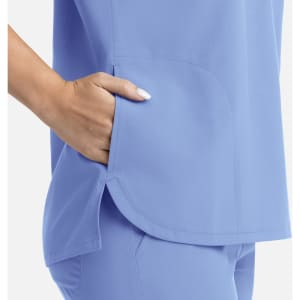 A light blue women's top featuring a dolman sleeve design and three pockets. It has a logo on it.
