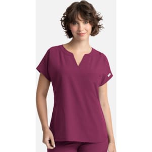 A woman models a deep burgundy women's top with a v-neck and short sleeves, featuring a front pocket.