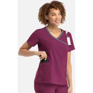 A women's mock wrap top in burgundy with contrast trim and pockets, featuring a logo.
