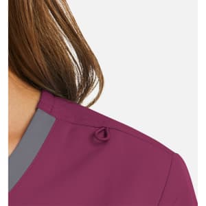 A close-up of a women's mock wrap top in a deep purple shade with grey contrast trim and a decorative detail on the shoulder.
