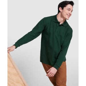 A green long-sleeve polo shirt displayed on a smiling model, paired with brown trousers. It features a logo.