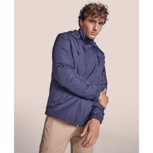 A water-repellent jacket in navy blue, featuring a hood and zip closure, modelled by a person.