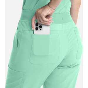 A pair of mint green flare leg pants with an elastic band and a phone tucked in the back pocket.